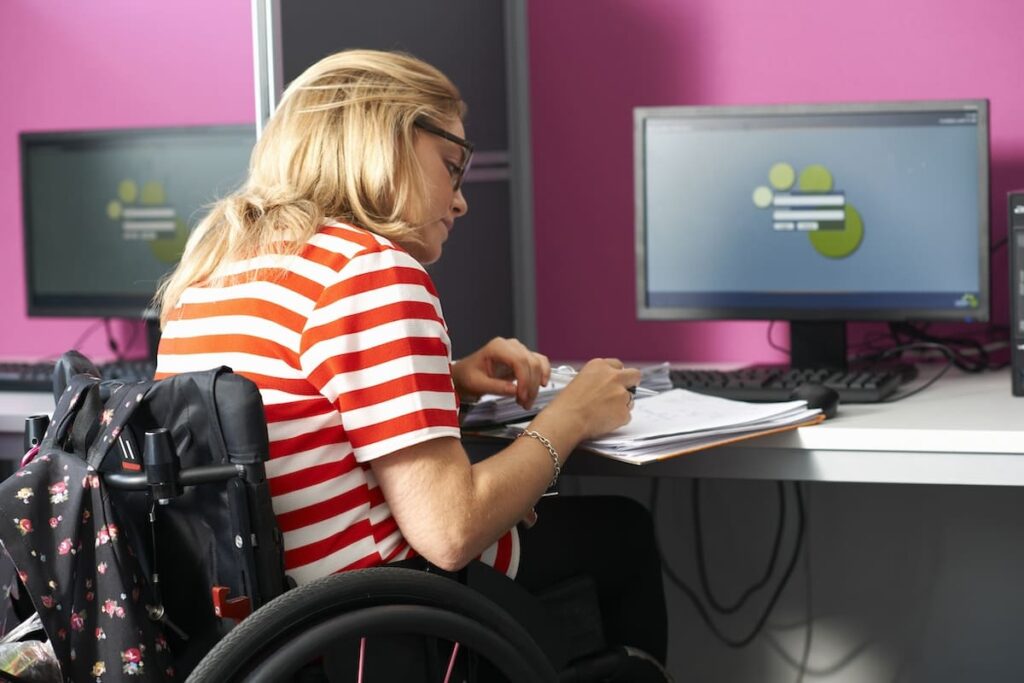 une femme en fauteuil roulant travaillant sur un ordinateur