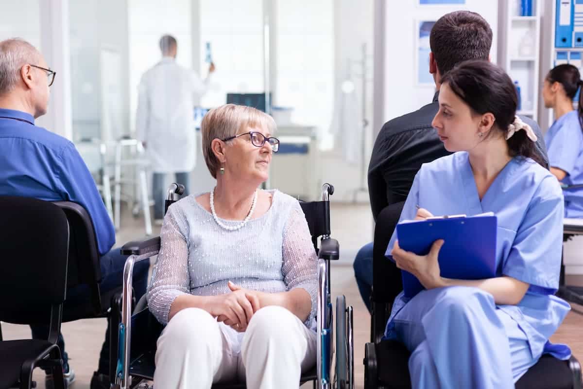 une femme en fauteuil roulant parle à une infirmière