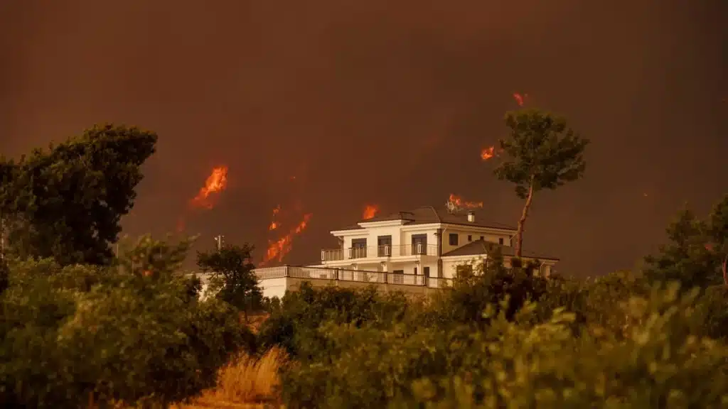 Maison entourée de flammes et de fumée lors d'un incendie de forêt en France