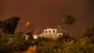 Maison entourée de flammes et de fumée lors d'un incendie de forêt en France