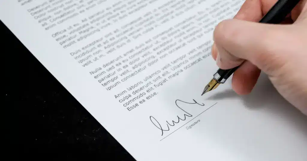 Violences commises en établissement médico-social : protéger votre proche 4 Mains écrivant une lettre administrative sur un bureau avec dossiers, lumière naturelle douce.