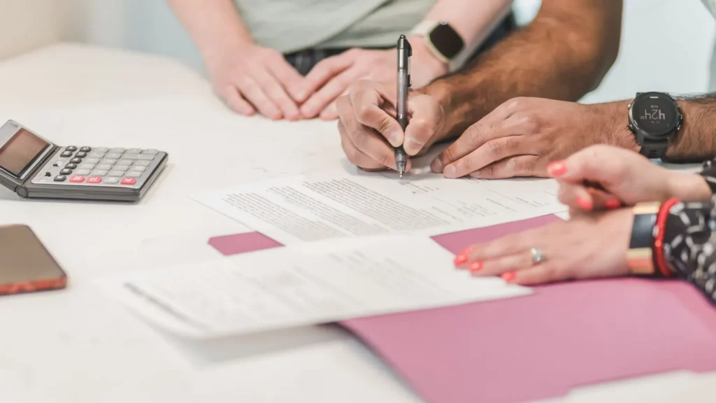 Personne guérie d'un cancer signant un contrat de prêt immobilier dans une banque