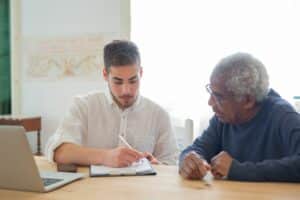 Avocat en droit du handicap 12 Un jeune homme et un homme plus âgé remplissent ensemble un formulaire devant un ordinateur portable
