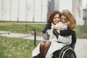 Avocat en droit du handicap 12 Une mère en fauteuil roulant serre sa fille dans ses bras en extérieur